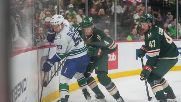 Minnesota Wild defenseman Jon Merrill (4) and defenseman Declan Chisholm (47) check Vancouver Canucks center Teddy Blueger (53) in the first period at Xcel Energy Center in St. Paul, Minn., on Feb. 19, 2024.